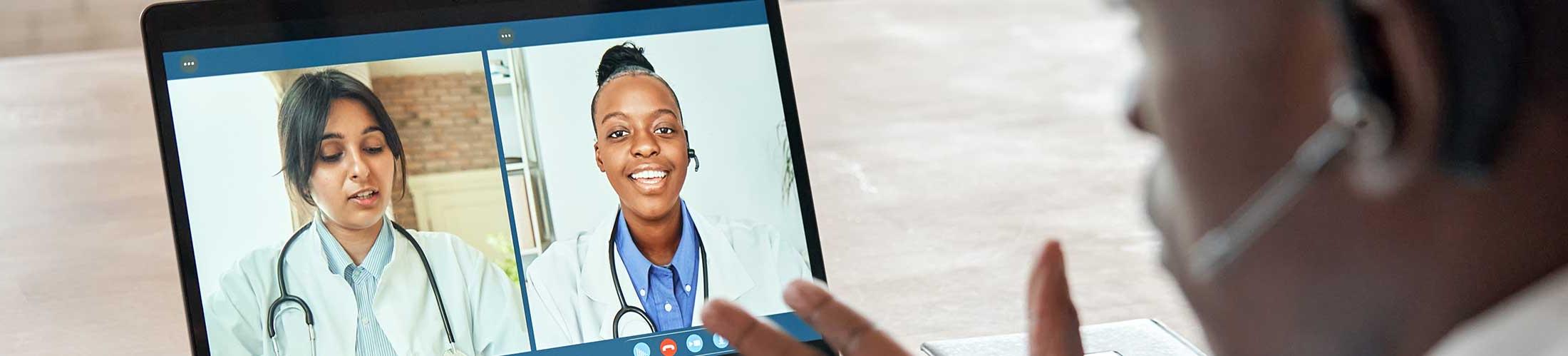 Man looking at computer screen with zoom meeting.