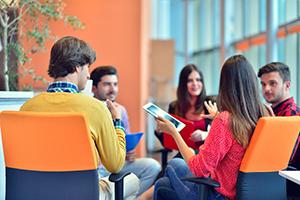 Group sitting in circle talking with one person holding a tablet.